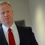 George Brauchler walking in a suit and tie